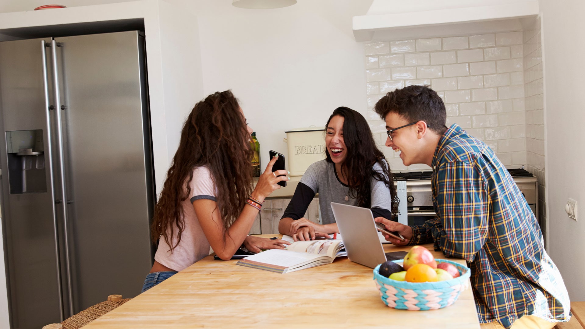 Young adults in a kitchen together looking at a phone